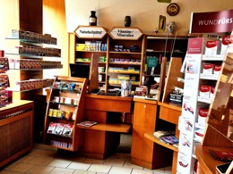 Innenansicht einer Apotheke mit Verkaufsregalen für Naturheilmittel, Vitamine und Beratungstheke.